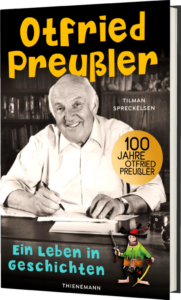 Das Buchcover zeigt Otfried Preußler lächelnd am Schreibtisch, umgeben von Büchern, und ein kleiner, gefiederter Holzspecht steht unten rechts. Die Farben sind warm und einladend.