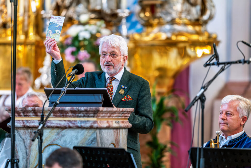 Josef M. Redl hielt während seiner Laudatio das von Hans Berger herausgegebene Liederheft „Dir zur Ehr’ mein Lied ich singe“ in die Höhe – ein Titel, der Bergers kirchenmusikalisches Wirken treffend zusammenfasst.