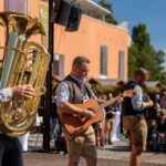 Musiker sorgen mit Blasmusik und Gitarren für Stimmung auf der Bühne.