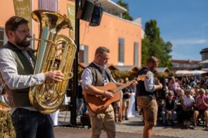 Musiker sorgen mit Blasmusik und Gitarren für Stimmung auf der Bühne.