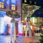 Stelzenläufer mit leuchtenden Regenschirmen bei den "Rosigen Zeiten" in der Rosenheimer Innenstadt.
