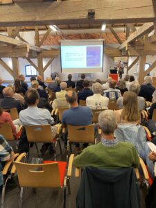 Blick in den Veranstaltungsraum mit Publikum und Vortrag.
