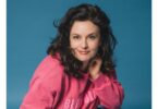 1: Angela Ascher als Kopfportrait vor blauem Hintergrund.
