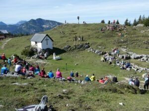 Panoramablick auf die Eggenalm mit Gottesdienstbesuchern und Alphornbläsern