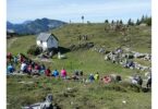 Panoramablick auf die Eggenalm mit Gottesdienstbesuchern und Alphornbläsern