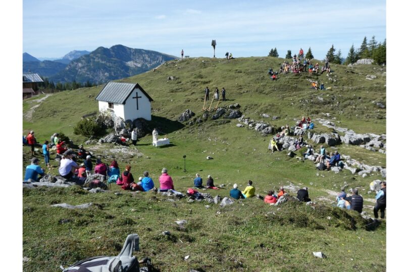 Panoramablick auf die Eggenalm mit Gottesdienstbesuchern und Alphornbläsern