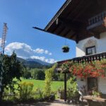 Balkon mit üppigen Blumen und Blick auf die Wiesen und Berge