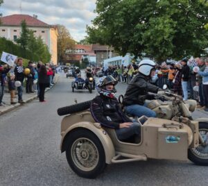 Eskorte und jubelnde Menschenreihen auf der Einfahrt ins Dorf