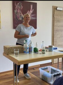 1: Vortragende stellt EM-Produkte auf einem Tisch vor