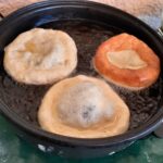 Schmalznudeln werden frisch in einer Pfanne ausgebacken.