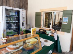 Regio-Box und Auslage mit hausgemachten Kuchen am Verkaufsfenster des Bergbauernladens.