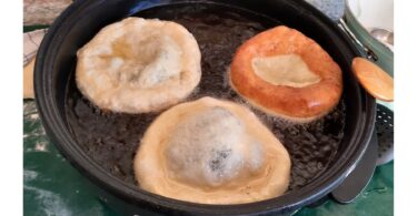 Schmalznudeln werden frisch in einer Pfanne ausgebacken.