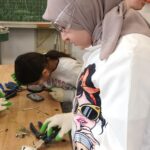 Schülerinnen und Schüler demontieren ausrangierte Handys und untersuchen die Bauteile.