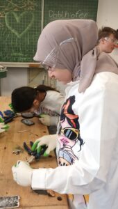 Schülerinnen und Schüler demontieren ausrangierte Handys und untersuchen die Bauteile.