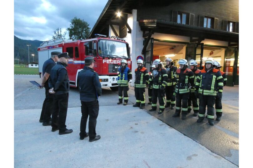 Schiedsrichter und Feuerwehrleute vor dem Feuerwehrhaus und Löschfahrzeug.