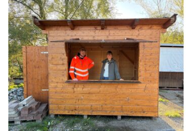Mitarbeiter des Bauhofs und eine Mitarbeiterin der Tourist‑Info stehen in einer reparierten Weihnachtsmarkthütte.