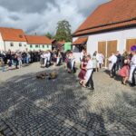 Kirwaburschen und Kirwamadla tanzen vor der voll besetzten Kulisse des Dorfplatzes.