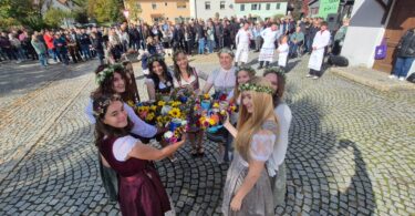 Kirwamadla stoßen mit geschmückten Krügen an.