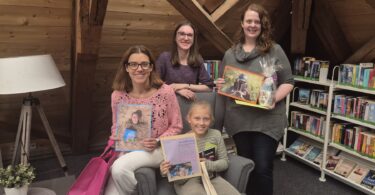 Büchereileiterin Melanie Schieber (hinten Mitte) überreichte den glücklichen Gewinnerinnen der Fotoaktion „Mein Lieblingsbuch & Ich“ ihre Preise (v. l. n. r.: Andrea Almer, Rika Stadler und Anja Keller).