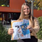 Johanna Schachtl präsentiert das Geschenk für die Neugeborenen: Kapuzenhandtuch und Bädergutschein.