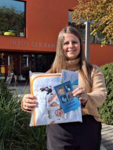 Johanna Schachtl präsentiert das Geschenk für die Neugeborenen: Kapuzenhandtuch und Bädergutschein.