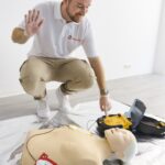 Defibrillator und Elektroden neben einer Reanimationspuppe