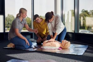 Johanniter zeigen und üben die Herzdruckmassage in einem Erste‑Hilfe‑Kurs