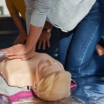Nahaufnahme einer Herzdruckmassage an einer Reanimationspuppe