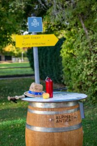 Startpunkt des Alpina Antica Trail: Weinfasstisch mit Wegweiser.