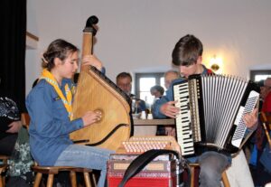 Jugendliche spielen Saiteninstrument und Akkordeon beim Hoagascht.