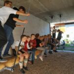 Kinder beim traditionellen Kirtahutsch auf der Schaukelbank.