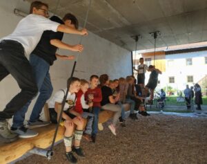 Kinder beim traditionellen Kirtahutsch auf der Schaukelbank.