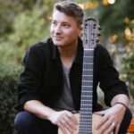 Daniel Stelter mit Gitarre in entspannter Pose.