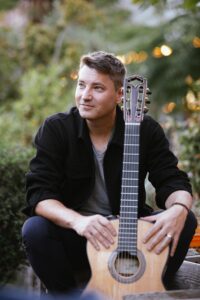 Daniel Stelter mit Gitarre in entspannter Pose.