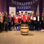Schäfflergruppe mit Auszeichnung auf der Bühne.