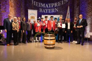 Schäfflergruppe mit Auszeichnung auf der Bühne.