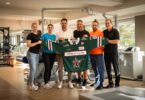 Vertreter der Gesundheitswelt Chiemgau und der Starbulls Rosenheim präsentieren ein Trikot im Reha-Zentrum.