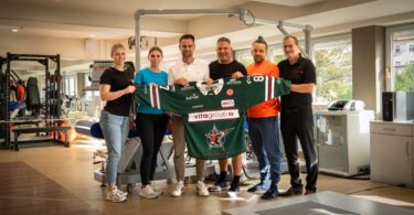 Vertreter der Gesundheitswelt Chiemgau und der Starbulls Rosenheim präsentieren ein Trikot im Reha-Zentrum.