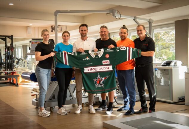 Vertreter der Gesundheitswelt Chiemgau und der Starbulls Rosenheim präsentieren ein Trikot im Reha-Zentrum.