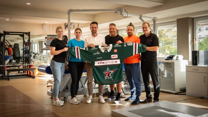 Vertreter der Gesundheitswelt Chiemgau und der Starbulls Rosenheim präsentieren ein Trikot im Reha-Zentrum.