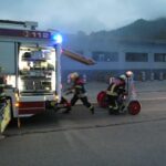 Aufbau am Löschfahrzeug mit Einsatzkräften vor der Halle.