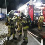 Atemschutzgeräteträger rüsten sich bei einem Löschfahrzeug aus.