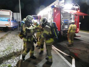 Atemschutzgeräteträger rüsten sich bei einem Löschfahrzeug aus.