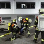 Einsatzkräfte versorgen eine Übungsverletzte an der Einfahrt.