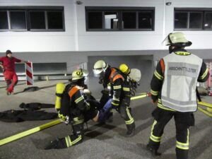 Einsatzkräfte versorgen eine Übungsverletzte an der Einfahrt.