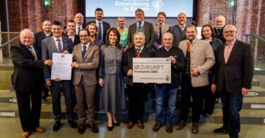 Die Vertreterinnen und Vertreter der Sieger des Staatspreises 2026: 1. Reihe v.l.n.r.: Franz Langstein (Verein für das Erinnern), Maximilian Heimerl (Landrat Mühldorf a. Inn), Sebastian Gaigl (ALE OB), StMin Michaela Kaniber, Dr. Heinz Utschig (BaySF a.D.), Balthasar Baumann (ALE OB), M.d.L. Sascha Schnürer, Martin Hartinger (BaySF); 2. Reihe v.l.n.r.: Heinrich Baumert (Verein für das Erinnern), Tobias Gehrmann (ADBV Mühldorf a.Inn), Edin Hamberger (Verein für das Erinnern), Dr. Jascha März (Stiftung Bayerische Gedenkstätten), Korbinian Baumann (Geschichtszentrum Mühldorf a.Inn), Monika Löffelmann (BaySF), StM a.D. Dr. Marcel Huber, Josef Grundner (1. Bgm. Ampfing), Josef Eisner (1. Bgm. Mettenheim), Barbara Donaubauer (ALE OB), Thomas Einwang (1. Bgm. Markt Buchbach)