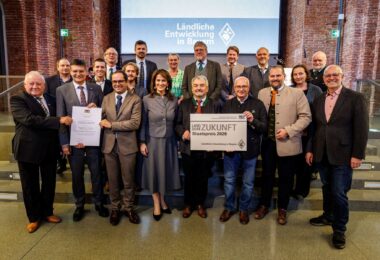 Die Vertreterinnen und Vertreter der Sieger des Staatspreises 2026: 1. Reihe v.l.n.r.: Franz Langstein (Verein für das Erinnern), Maximilian Heimerl (Landrat Mühldorf a. Inn), Sebastian Gaigl (ALE OB), StMin Michaela Kaniber, Dr. Heinz Utschig (BaySF a.D.), Balthasar Baumann (ALE OB), M.d.L. Sascha Schnürer, Martin Hartinger (BaySF); 2. Reihe v.l.n.r.: Heinrich Baumert (Verein für das Erinnern), Tobias Gehrmann (ADBV Mühldorf a.Inn), Edin Hamberger (Verein für das Erinnern), Dr. Jascha März (Stiftung Bayerische Gedenkstätten), Korbinian Baumann (Geschichtszentrum Mühldorf a.Inn), Monika Löffelmann (BaySF), StM a.D. Dr. Marcel Huber, Josef Grundner (1. Bgm. Ampfing), Josef Eisner (1. Bgm. Mettenheim), Barbara Donaubauer (ALE OB), Thomas Einwang (1. Bgm. Markt Buchbach)