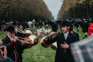 Jagdhornbläser spielen vor der Meute.