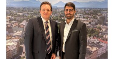 René Zumtobel und Abuzar Erdogan im Rathausfoyer vor einem Panoramabild von Rosenheim.