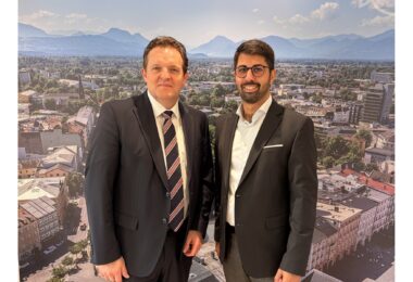 René Zumtobel und Abuzar Erdogan im Rathausfoyer vor einem Panoramabild von Rosenheim.